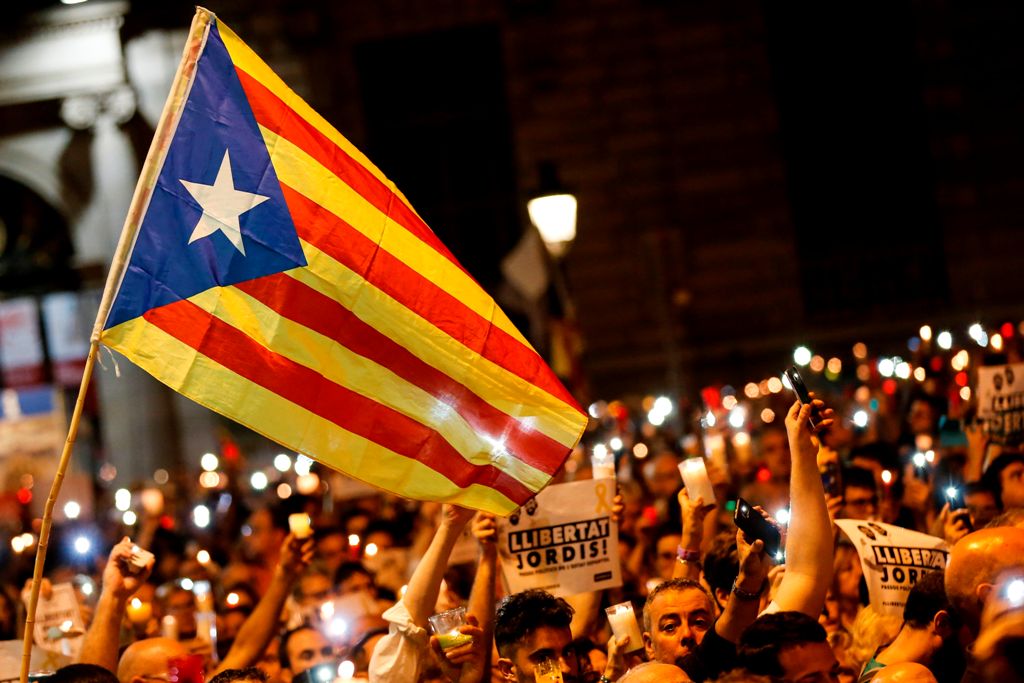 This file photo taken on October 17, 2017 shows people holding candles and a Catalan pro-independence 'Estelada' flag during a demonstration in Barcelona against the arrest of two Catalan separatist leaders. / AFP.