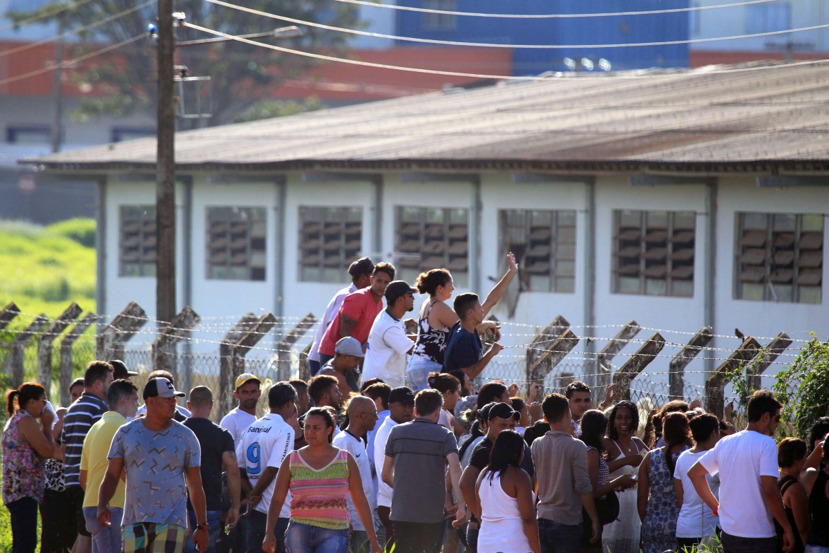 This photo released by Brazilian newspaper O Popular shows prisoners' relatives waiting for information outside the 