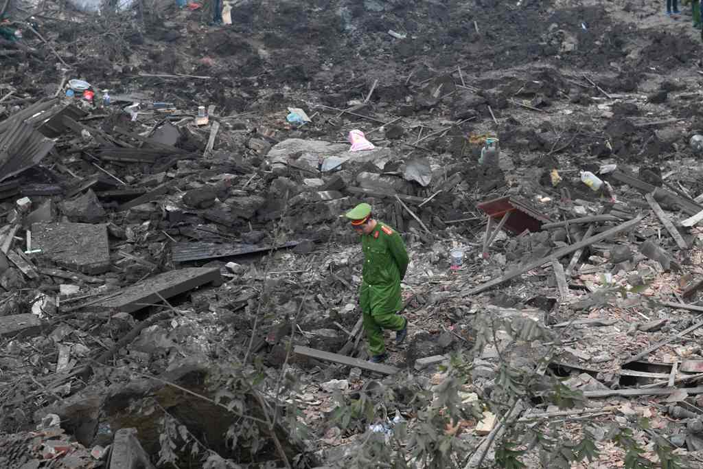 A policeman walks across debris after a big explosion razed five homes and shattered windows of surrounding buildings in the northern province of Bac Ninh on January 3, 2018. / AFP / HOANG DINH NAM