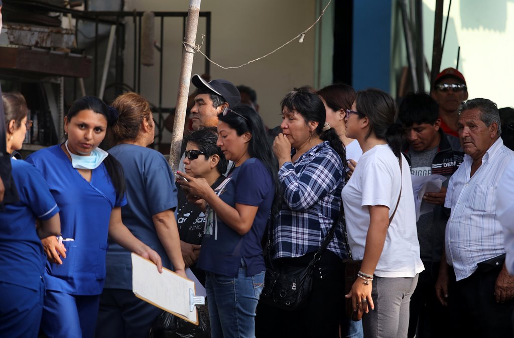 Relatives of the victims of a bus that crashed with a truck and careened off a cliff along a sharply curving highway north of Lima, wait outside a hospital morgue in Chancay, Peru, January 3, 2018. REUTERS/Guadalupe Pardo