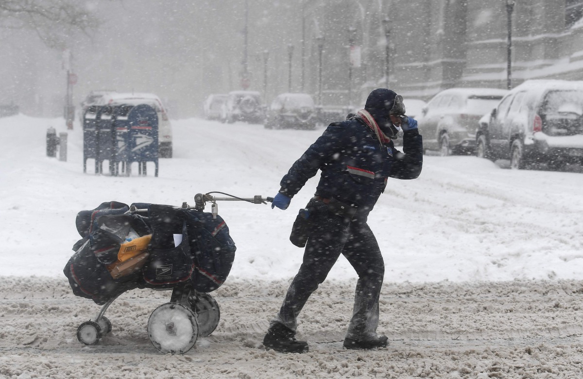 A mail delivery person pulls her cart through the snow on January 4, 2018 in Brooklyn, New York. AFP / Angela Weiss