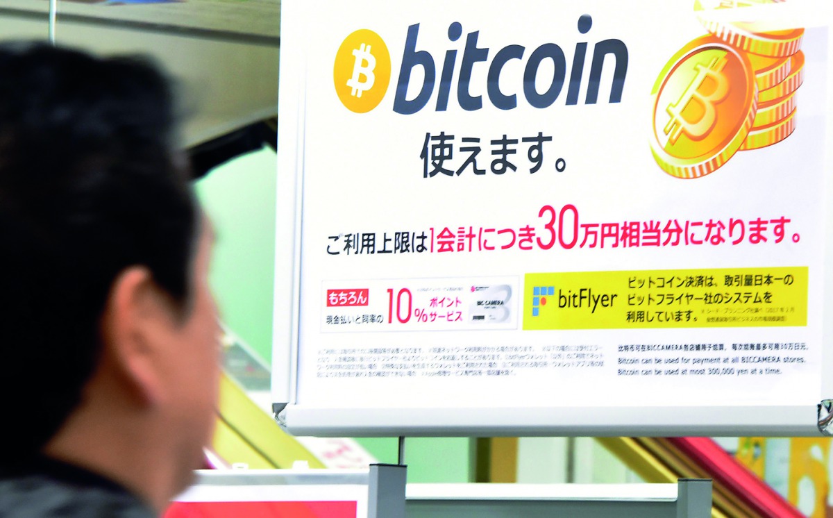 A man walks past a poster that informs customers that bitcoin can be used in this shop in Tokyo on January 06, 2018. Bitcoin is recognised as legal tender in the world's third-biggest economy and nearly one third of global bitcoin transactions in December