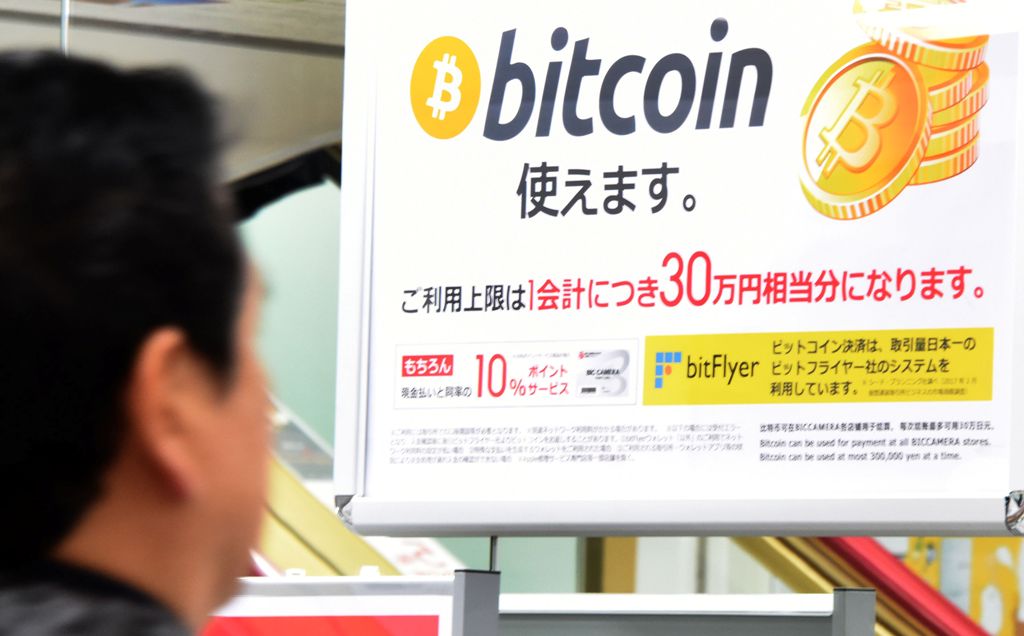 A man walks past a poster that informs customers that bitcoin can be used in this shop in Tokyo on January 06, 2018. / AFP / Toru YAMANAKA 