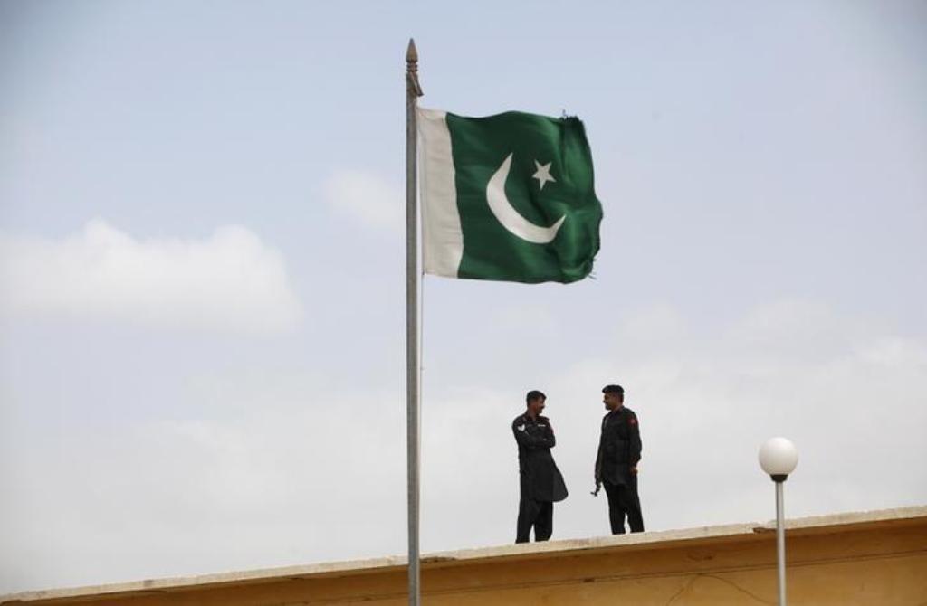  File photo of Pakistani flag flies on a mast as paramilitary Frontier Corps soldiers talk, August 23, 2013. REUTERS/Akhtar Soomro/Files 