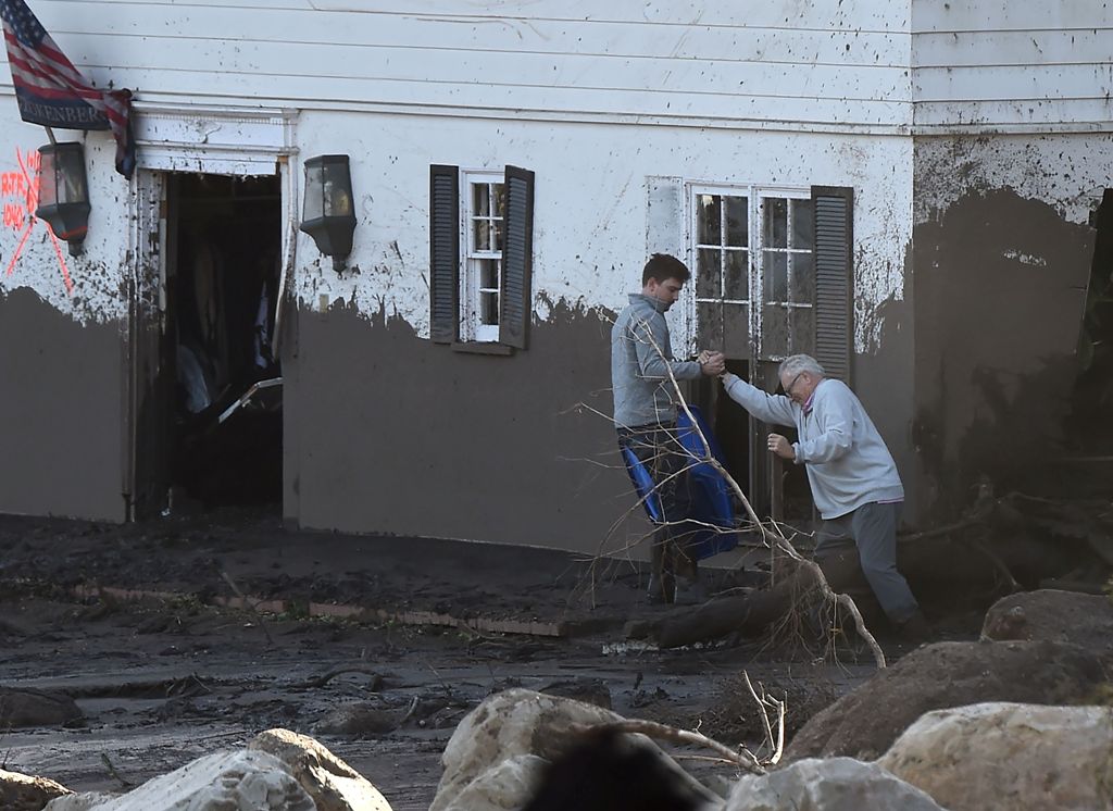 An older man is hekled as he tries to enter his mud-damaged home, January 10, 2018 in Montecito, California.  AFP / Robyn Beck
