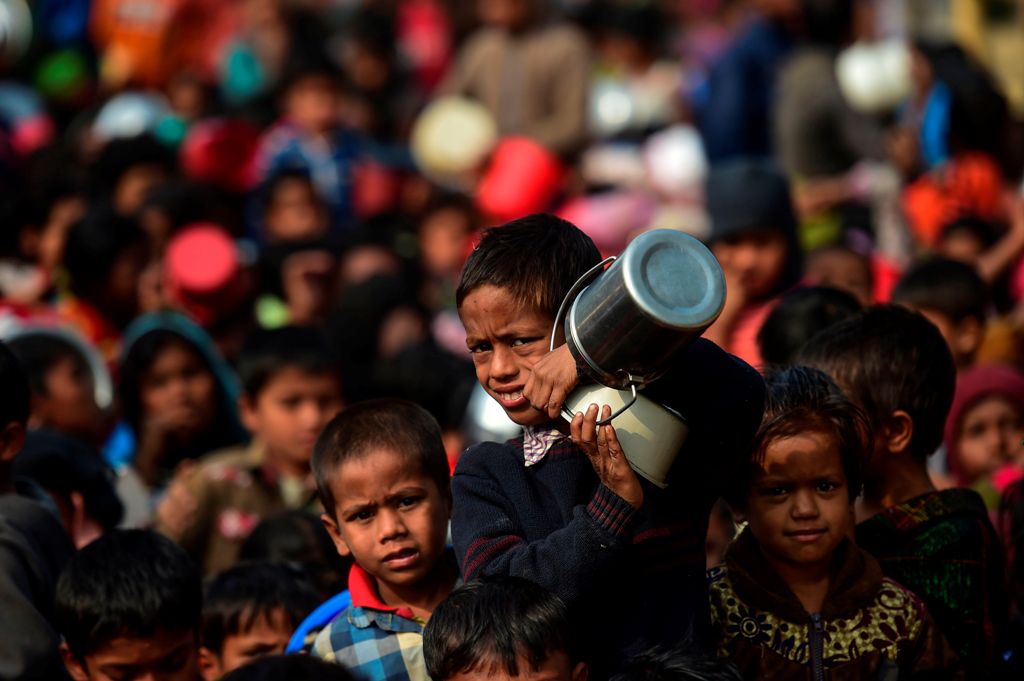 A Rohingya Muslim refugee waits with others for food aid at Thankhali refugee camp in Bangladesh's Ukhia district on January 12, 2018. / AFP / Munir UZ ZAMAN