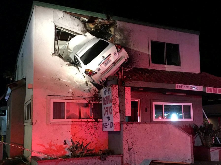 A car dangles off the second floor of a building after speeding into a median and going airborne, according to local media, in Santa Ana, California, U.S., January 14, 2018, in this picture obtained from social media. OCFA PIO/via REUTERS