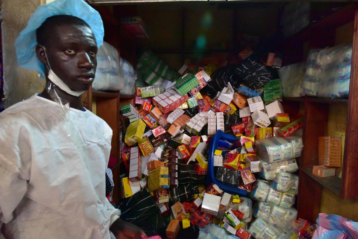 A Health Ministry employee taking part in an operation to empty shops selling fake medicine during a raid monitored by police officers against shops selling counterfeit drugs at the Adjame market in Abidjan on May 03, 2017. AFP / Issouf Sanogo