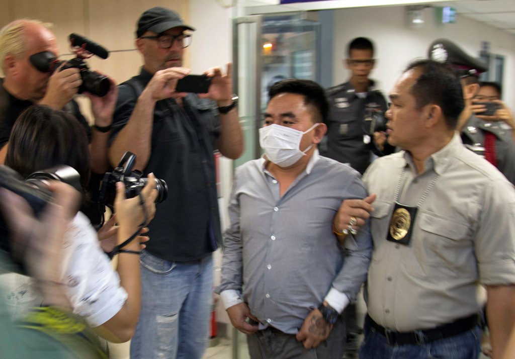 A handout photo made available by Freeland, a frontline counter-trafficking organization, shows wildlife trafficking suspected Bach Van Minh, also known as Boonchai Bach (C), being escorted by Thai police officers at the Suvarnabhumi Airport's police stat