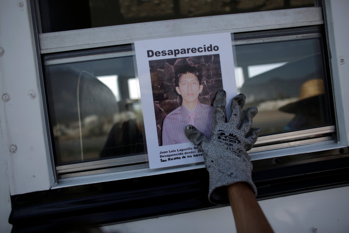 A woman holds the photograph of a relative lost in fight between drug gangs during a serach at Escobedo on the outskirts of Monterrey, Mexico, August 12, 2016. (Reuters) 