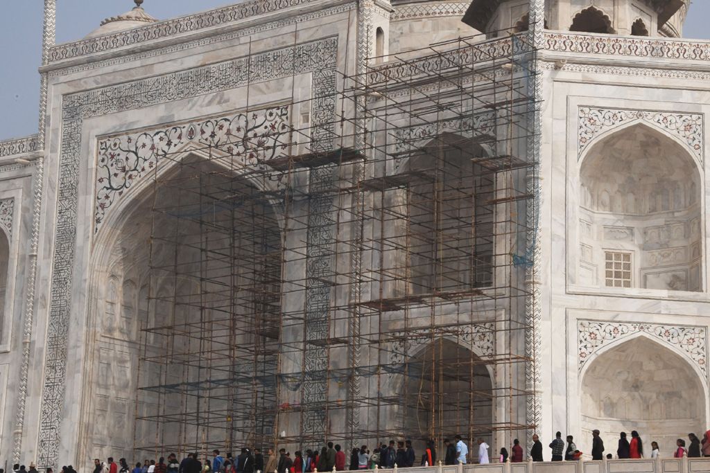 This photograph taken on January 3, 2018 shows tourists visiting the Taj Mahal near scaffolding installed for the conservation work at the monument in the Indian city of Agra. / AFP / DOMINIQUE FAGET 