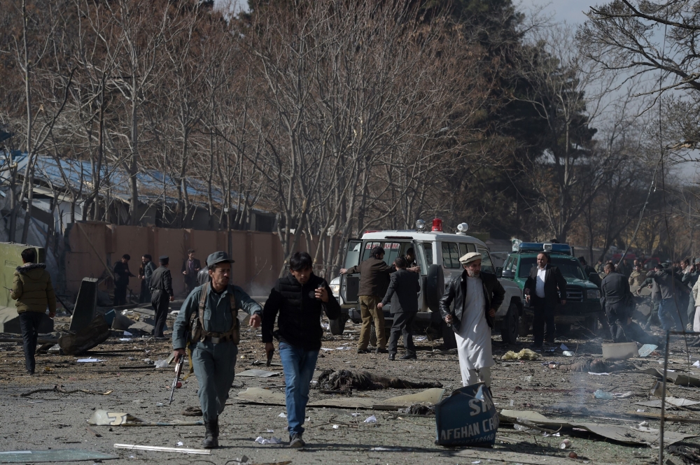 Afghan volunteers and policemen carry injured men on an ambulance at the scene of a car bomb exploded in front of the old Ministry of Interior building in Kabul on January 27, 2018.   AFP / WAKIL KOHSAR