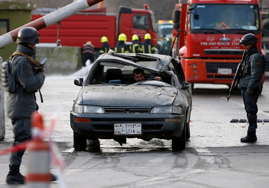 Afghan police officers keep watch while a man drives his damaged car at the site of a car bomb attack in kabul, Afghanistan January 27, 2018. REUTERS/Omar Sobhani	