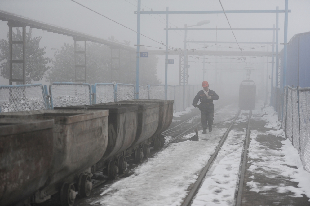 FILE PHOTO: A coal worker walks next to wagons amid smog in Huaibei, Anhui province, China January 29, 2018. REUTERS/Stringer/File Photo