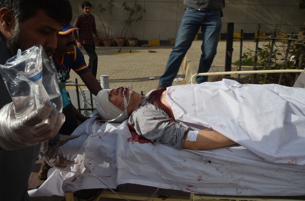 Pakistani paramedics push a stretcher carrying an injured Chinese national to an hospital after an attack by gunmen in Karachi on February 5, 2018. / AFP / ASIF HASSAN