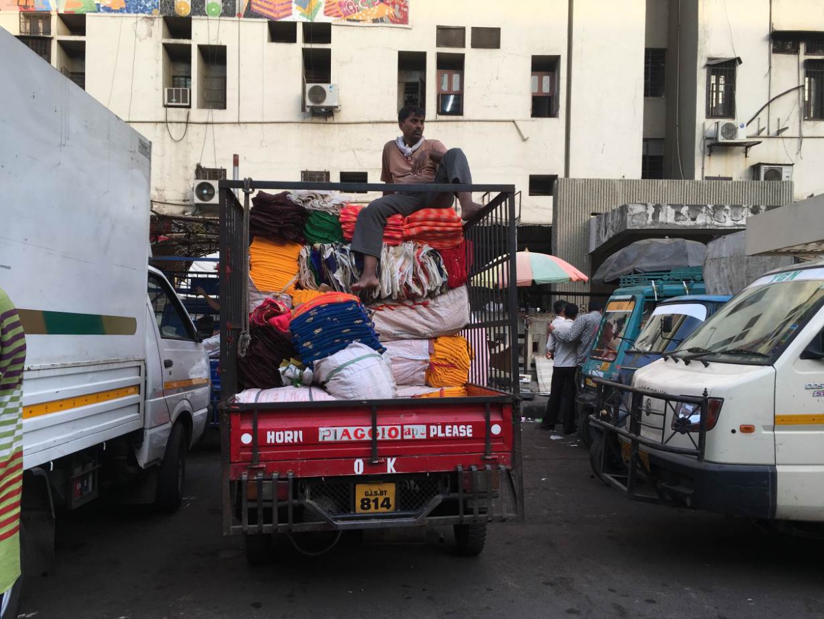A man rests on a pile of fabric in the textile market of Surat, India (TRF / Roli Srivastava) 
