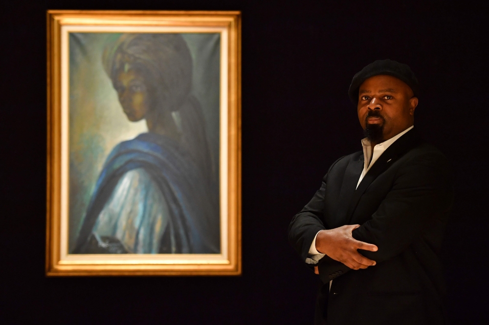 Nigerian author Ben Okri poses with a work of art by Nigerian painter and sculptor Ben Enwonwu entitled 'Tutu' expected to realise 200,000-300,000 GBP (278000-417,000 USD) at auction in Bonhams auction house London on February 7, 2018.  AFP / Ben Stansall