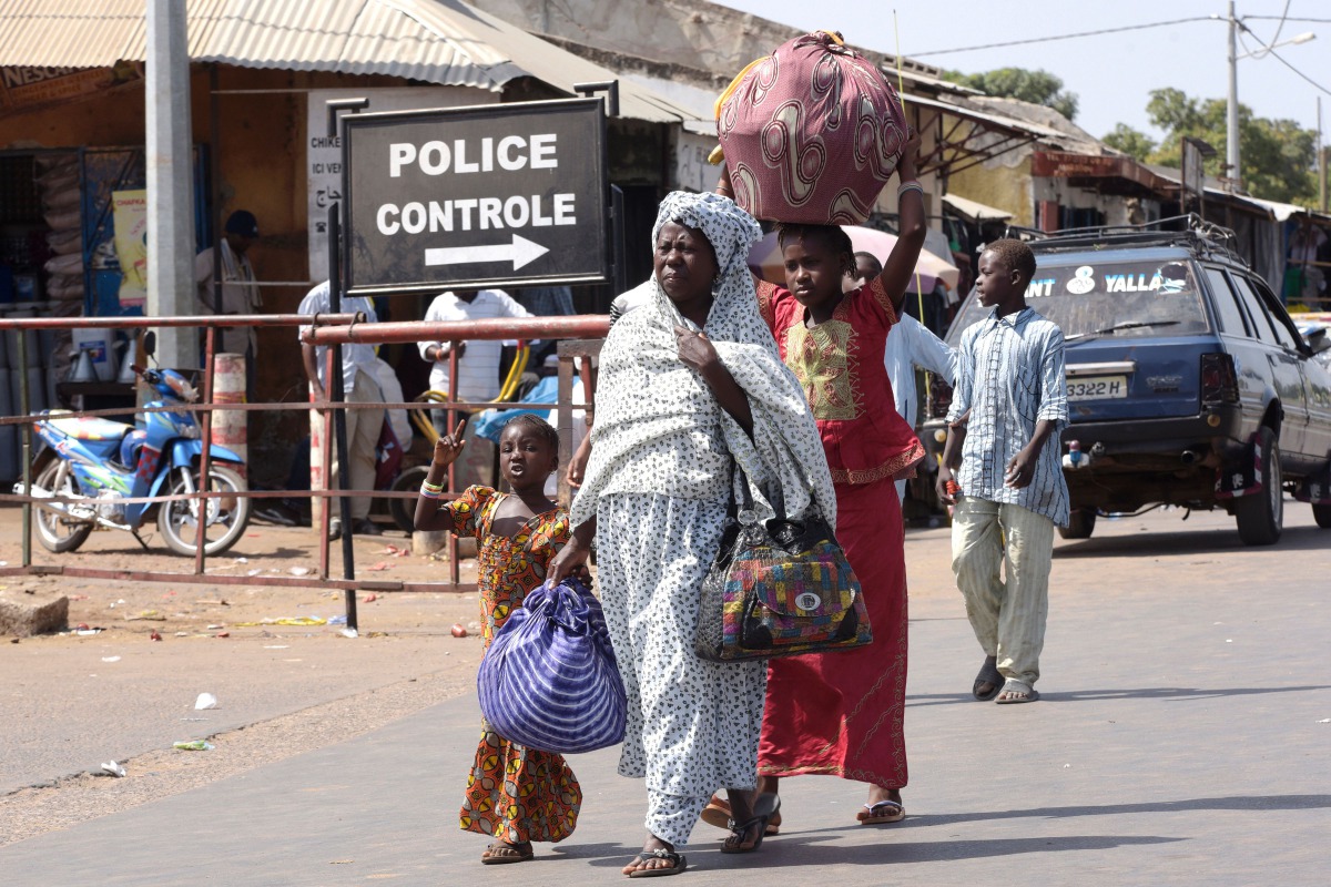 A woman and children walk through the Senegalese-Gambia border town of Karangon,  May 10,  2016. AFP / seyllou