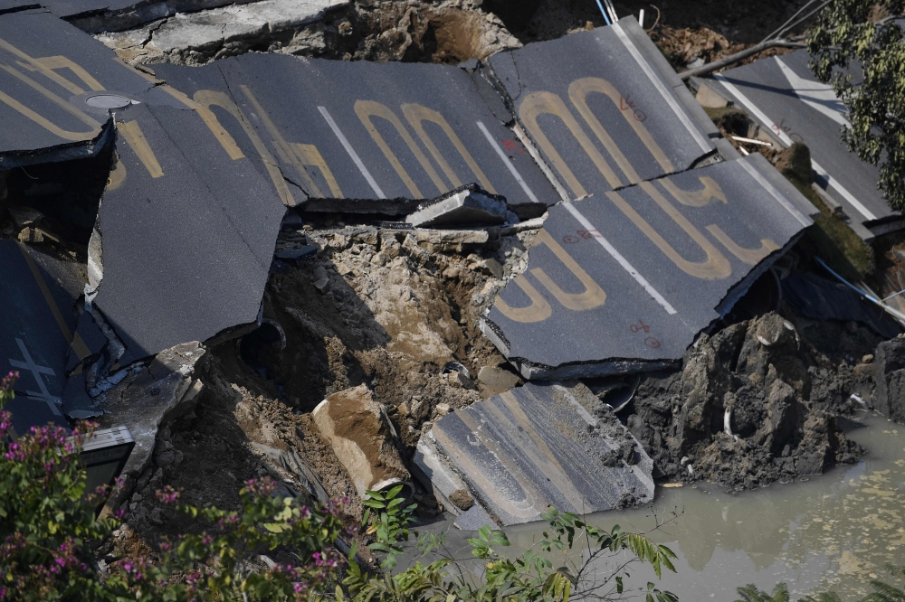 A damaged section of road is seen at an accident site after a road collapse in Foshan in China's southern Guangdong province on February 8, 2018. China OUT / AFP / 