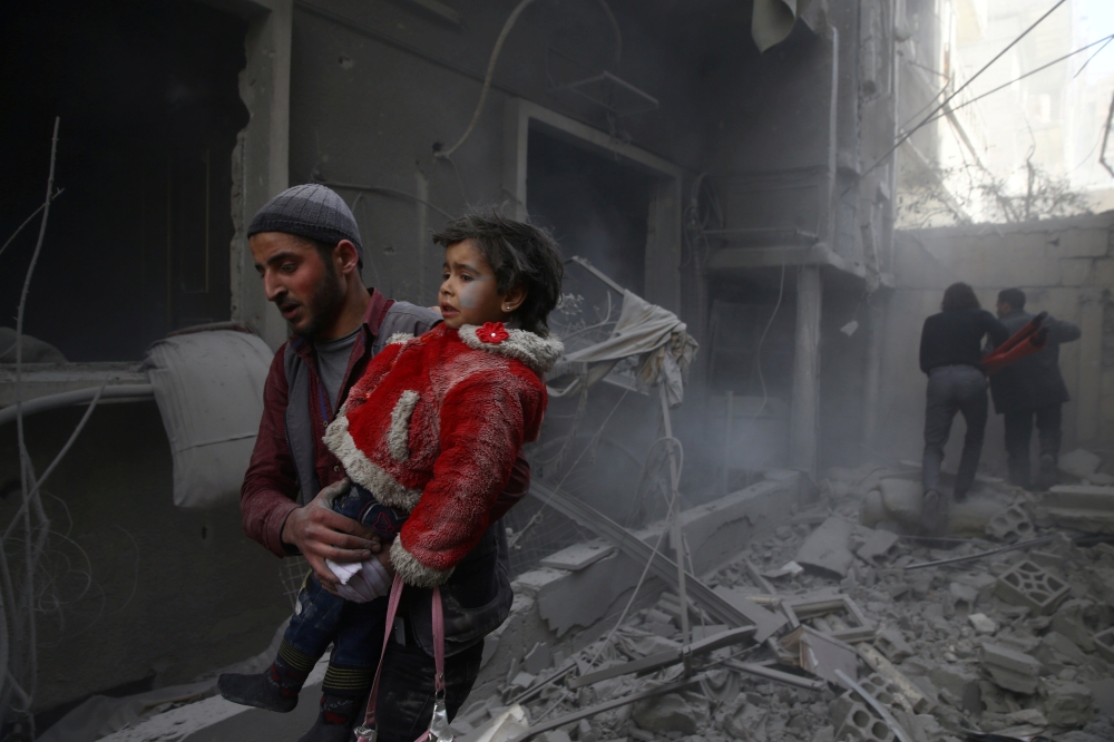 A man holds a child after an airstrike in the besieged town of Douma, Eastern Ghouta, Damascus, Syria February 7, 2018. REUTERS/Bassam Khabieh
