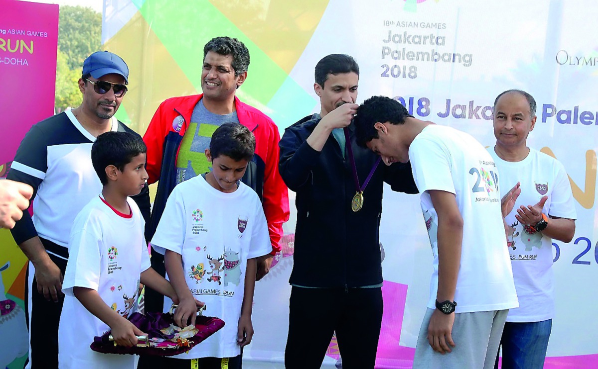 QOC Secretary-General Jassim Al Buenain presenting schoolchildren their medals.