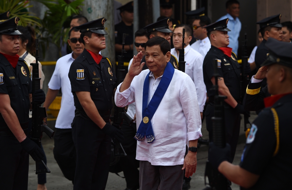 This photo taken on February 6, 2018 shows Philippine President Rodrigo Duterte (C) saluting as he arrives to attend the Bureau of Customs anniversary in Manila.  AFP / Ted Aljibe