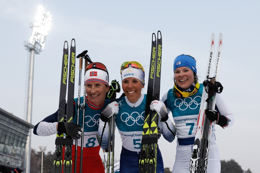 Sweden's Charlotte Kalla (C), flanked by Norway's Marit Bjoergen (L) and Finland's Krista Parmakoski celebrate at the end of the women's 7.5km + 7.5km cross-country skiathlon event at the Alpensia cross country ski centre during the Pyeongchang 2018 Winte