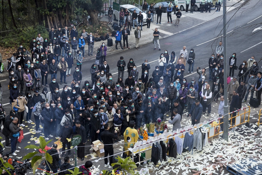 Mourners attend the crash site for a memorial service in hong kong on February 11, 2018, for victims of a bus crash that killed 19 people on February 10. AFP / ISAAC LAWRENCE