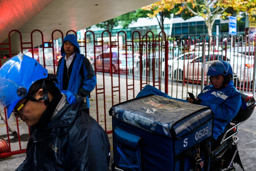 File photo of deliverymen waiting on the roadside for orders of food to deliver in Shanghai, December 15, 2017.  AFP / CHANDAN KHANNA 