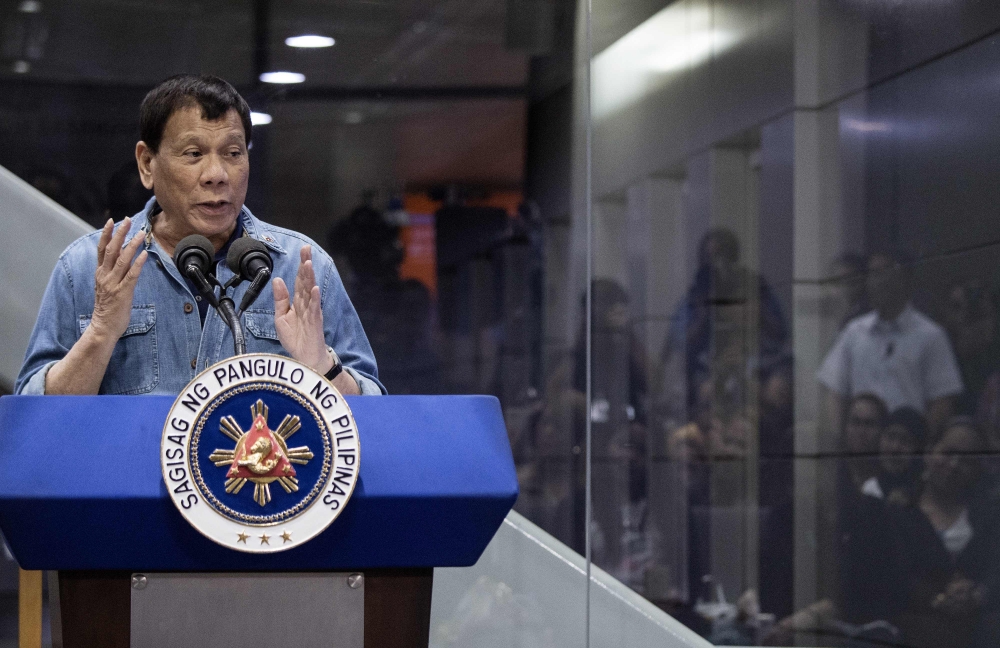 File photo of Philippine President Rodrigo Duterte delivering his speech to overseas Filipina workers (OFW) that arrived in Manila from Kuwait are at the Manila International Airport on February 13, 2018.  / AFP / NOEL CELIS