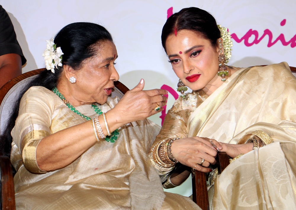 Indian Legendary Bollywood playback singer Asha Bhosle (L) and actress Rekha (R) talk during the fifth edition of 'Yash Chopra National Memorial Awards 2018' in Mumbai late on February 16, 2018. / AFP / - 