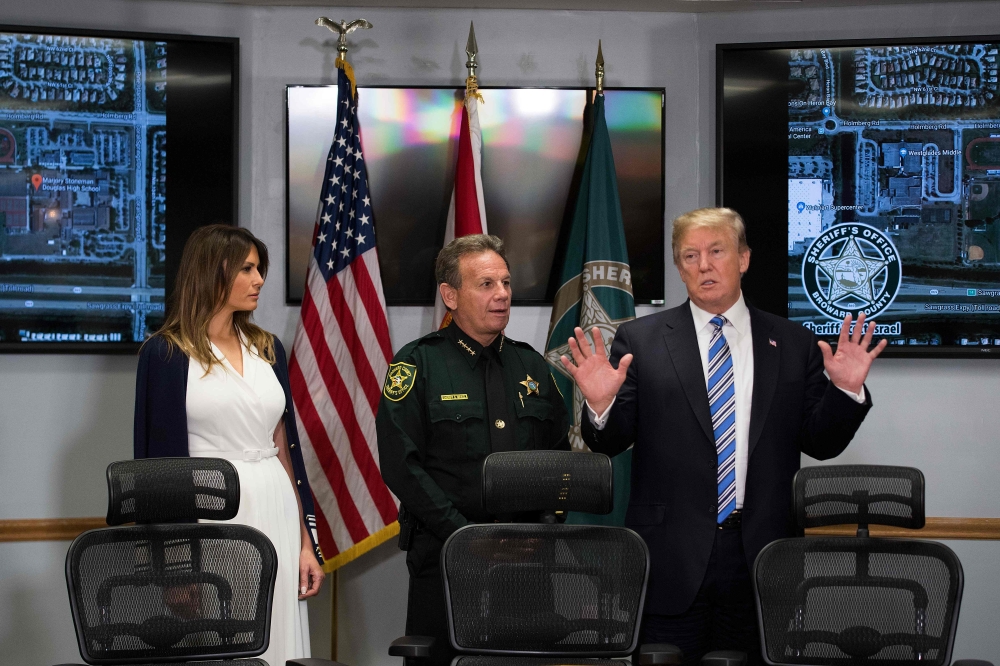 US President Donald Trump (R) and First Lady Melania Trump (L) speak with Broward County Sheriff Scott Israel (C) while visiting first responders at Broward County Sheriff's Office in Pompano Beach, Florida, on February 16, 2018, three days after a mass s