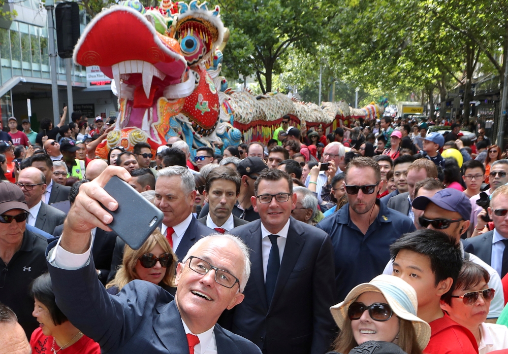Australian Prime Minister Malcolm Turnbull takes a selfie as he walks with Victorian Premier Daniel Andrews and members of the public during a parade as part of the Chinese New Year Festival in Melbourne, Australia, February 18, 2018. AAP/David Crosling/v