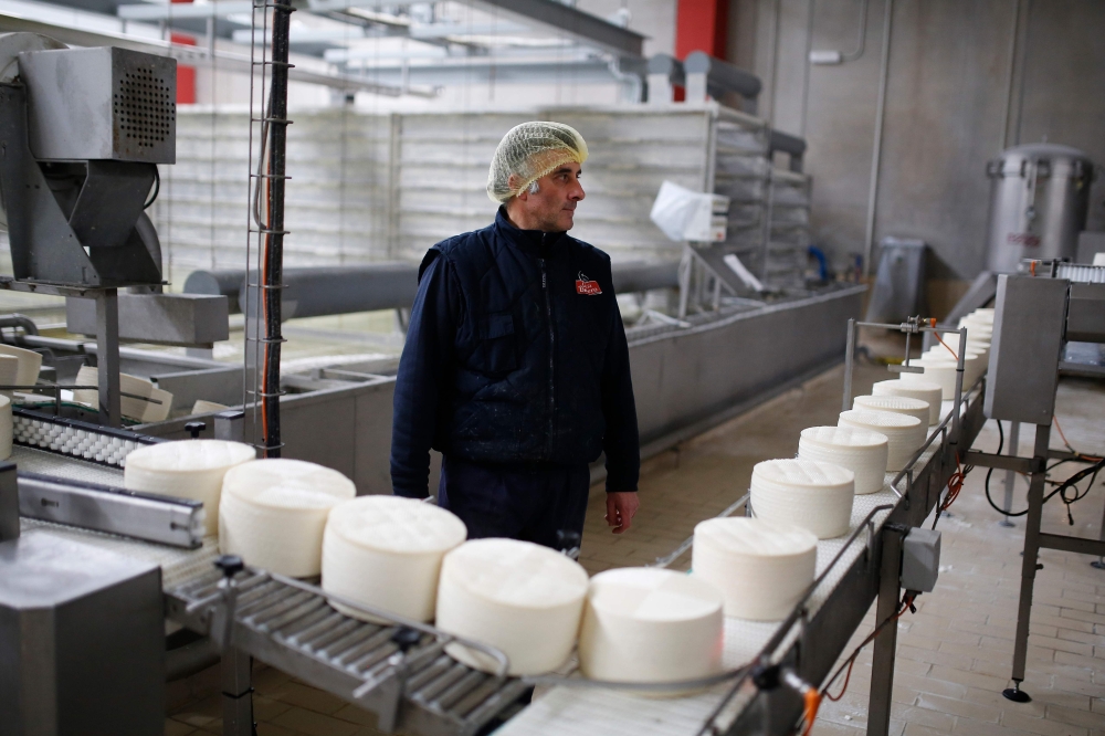 An employee of 'Garcia Baquero' cheese manufacturer works at the production line of the company's factory in Alcazar de San Juan on February 15, 2018. AFP / Benjamin Cremel 