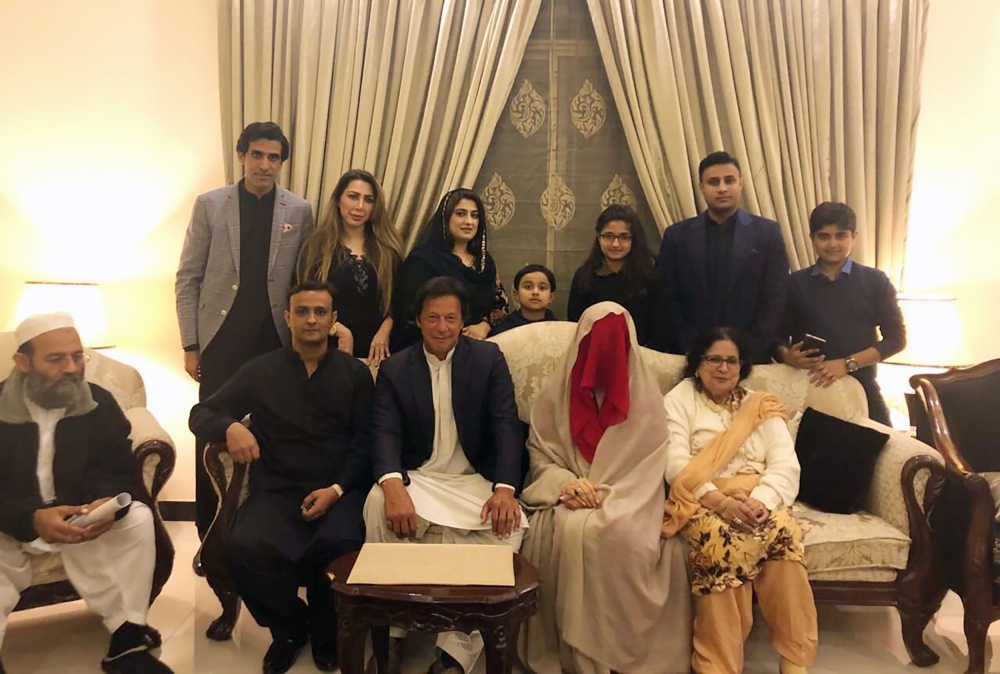 This handout picture released by Pakistan Tehreek-i-Insaaf (PTI) on February 19, 2018, shows Pakistani cricketer-turned-opposition leader and head of the Pakistan Tehreek-i-Insaaf (PTI) party Imran Khan (C) posing for a photograph with his new wife Bushra