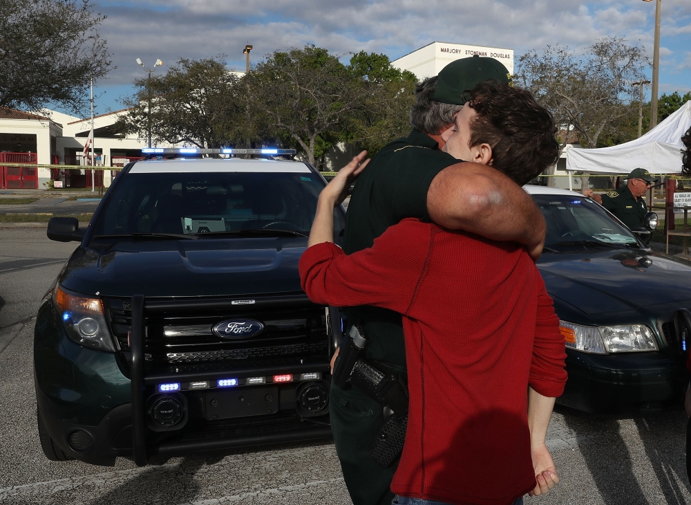 Chris Grady a senior at Marjory Stoneman Douglas High School hugs Broward County Sheriff officer Brad Griesinger as he guards the front gate of the school on February 18, 2018 in Parkland, Florida. Joe Raedle/Getty Images/AFP 