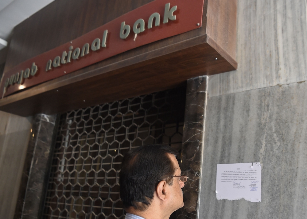 A man reads a notice by the Indian Central Bureau of Investigation (CBI) stating that the Brady House branch of the Punjab National Bank (PNB) has been sealed next to the entrance of the branch in Mumbai on February 19, 2018.  AFP / INDRANIL MUKHERJEE