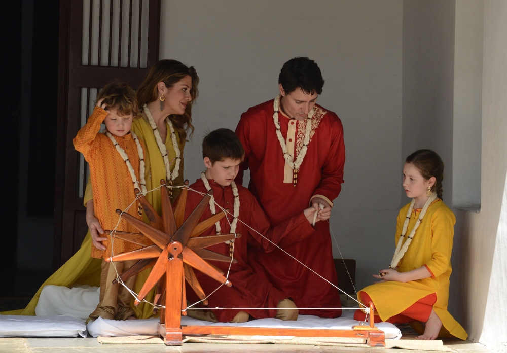 Canadian Prime Minister Justin Trudeau (2nd R) and his wife Sophie Gregoire Trudeau (2nd L) sit with their daughter Ella-Grace (R), and their sons Xavier (3rd L) and Hadrien (L) as they try out a ceremonial spinning wheel during their visit to Gandhi Ashr