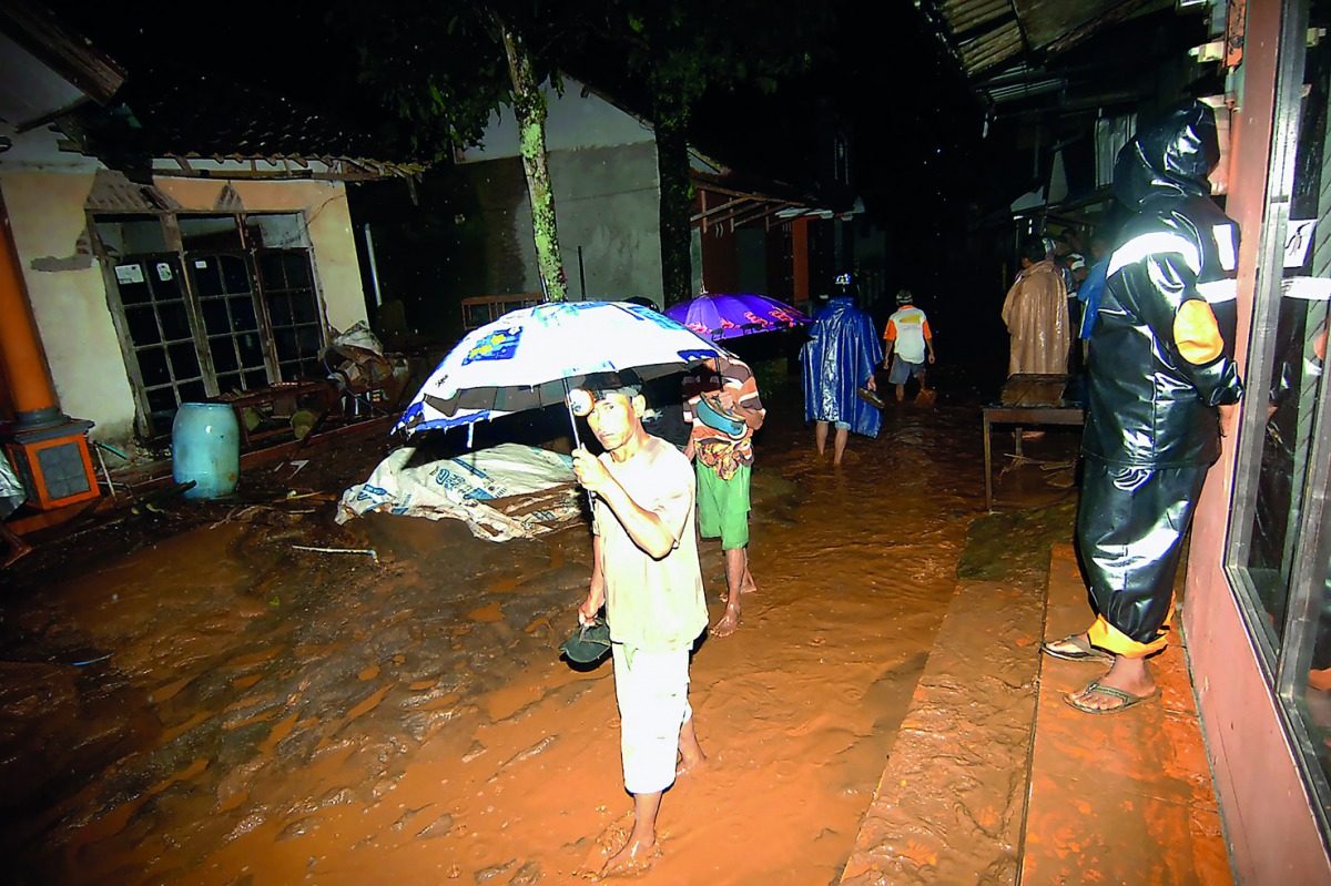 Residents walk along a street covered in mud after an avalanche of mud and rocks struck Pasirpanjang in Brebes district, Central Java, on February 22, 2018.  AFP