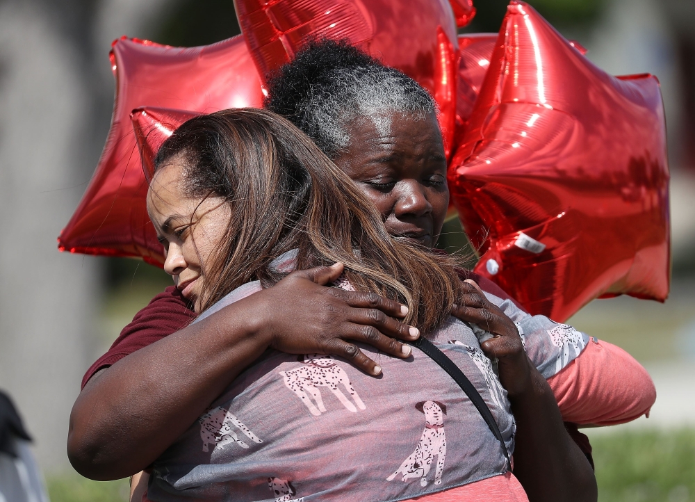 Kay Blake (L) hugs school bus driver Pearlie Corker as they visit in front of Marjory Stoneman Douglas High School as teachers and staff are allowed to return to the school for the first time since the mass shooting on campus on February 23, 2018 in Parkl