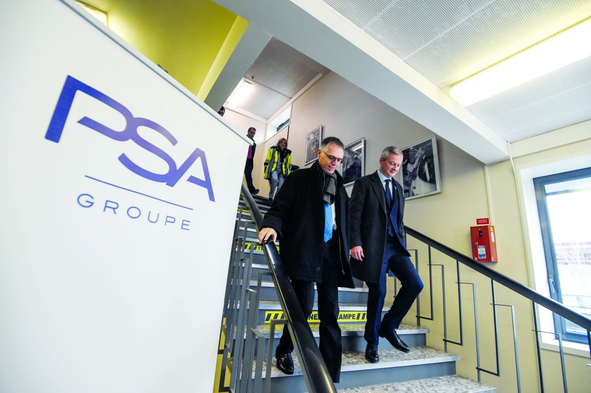 French Economy Minister Bruno Le Maire (R) walks with chairman of the managing board of French carmaker PSA Peugeot Citroen Carlos Tavares during a visit to the PSA car plant in Mulhouse on February 23, 2018.  AFP / Sebastien Bozon 