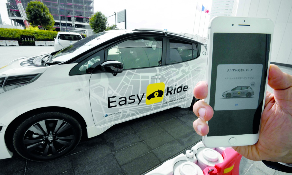 This photo taken on February 21, 2018 shows a man calling a Nissan electric vehicle Leaf equipped with an auto-driving system with exclusive software for smart phones, during a field test press preview in Yokohama, Kanagawa prefecture.  AFP / Toru Yamanak