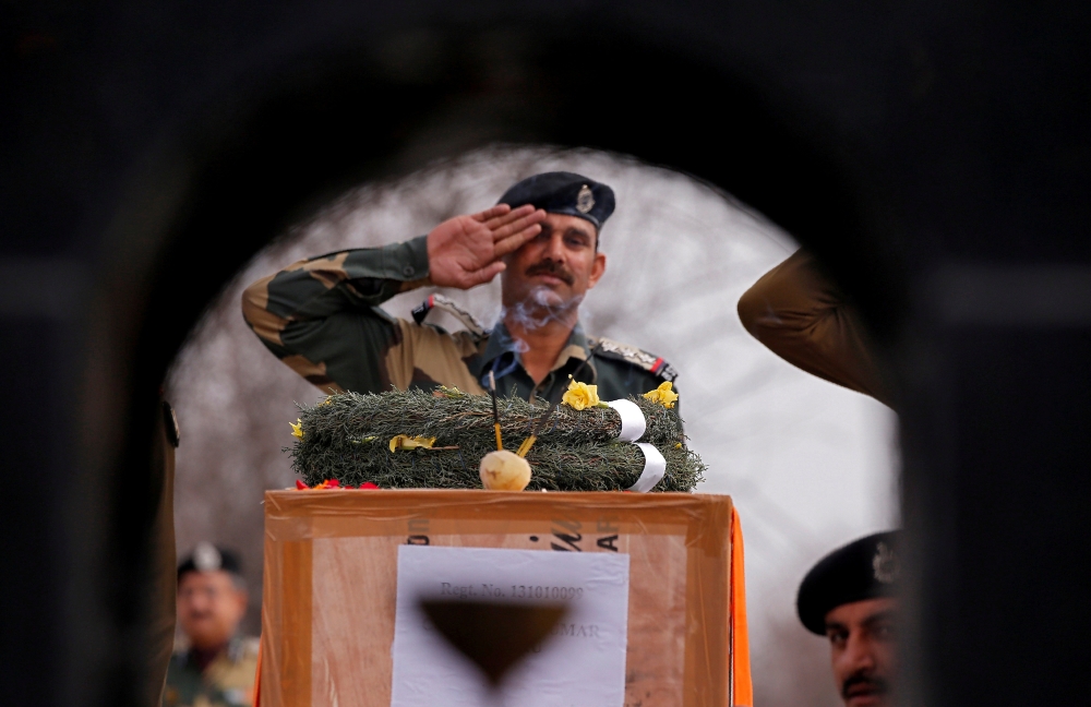 Incense sticks burn as an Indian Border Security Force (BSF) officer salutes to a coffin containing the body of a soldier, who according to BSF died on Wednesday after he was injured in a gunfire on Tuesday at the Line of Control (LOC) with Pakistan in Ka