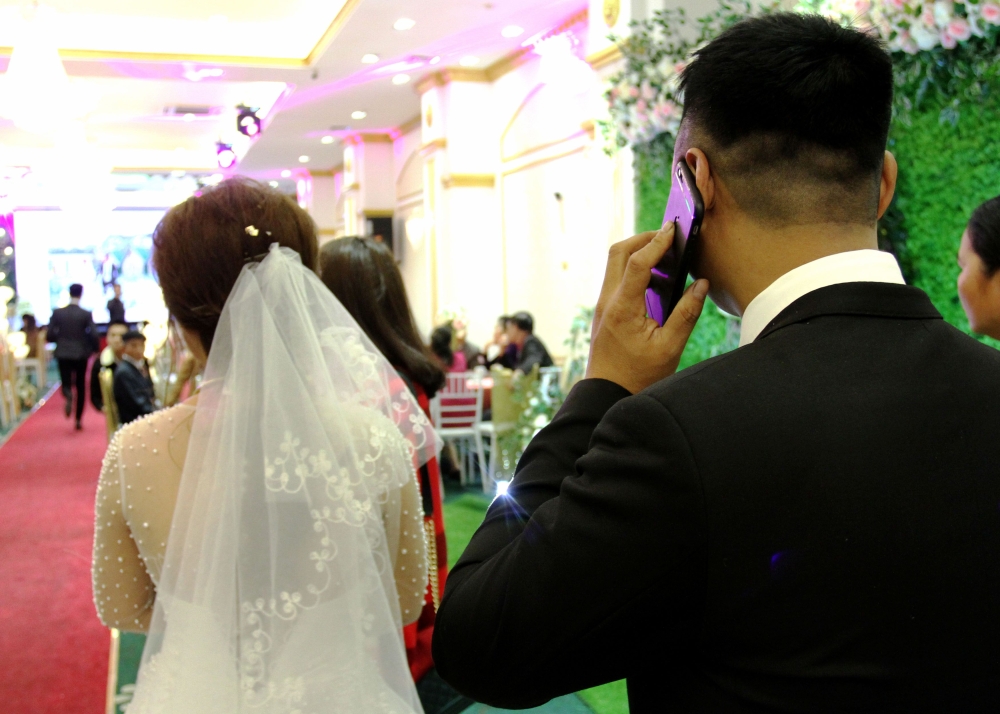File photo of Huong (L) and Quan (R) enter the hall for their wedding party in Hanoi, January 23, 2018. / AFP / Nhac Nguyen 