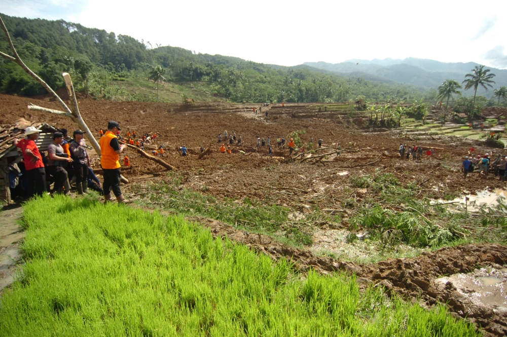 Members of a rescue team join villagers as they search for victims of a landslide triggered by a heavy rain in Brebes, Central Java province, on February 23, 2018. / AFP / - 