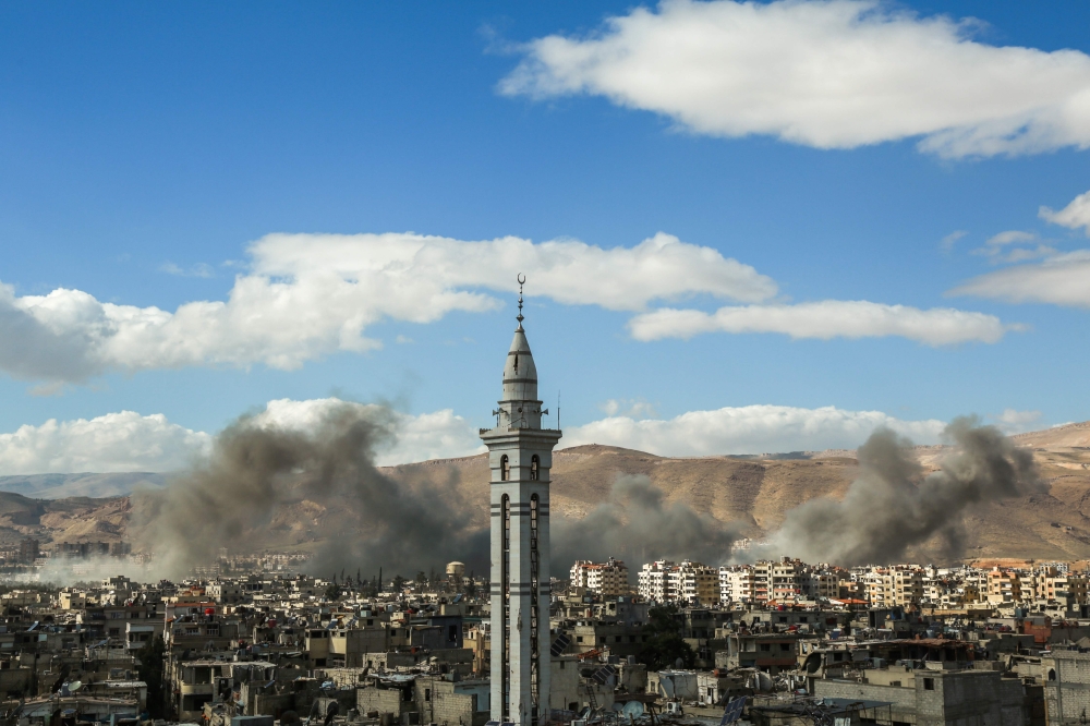 A picture taken on February 27, 2018, shows smoke plumes rising during reported regime bombardment Syrian rebel-held town of Douma, in the besieged Eastern Ghouta region on the outskirts of the capital Damascus. / AFP / HAMZA AL-AJWEH
