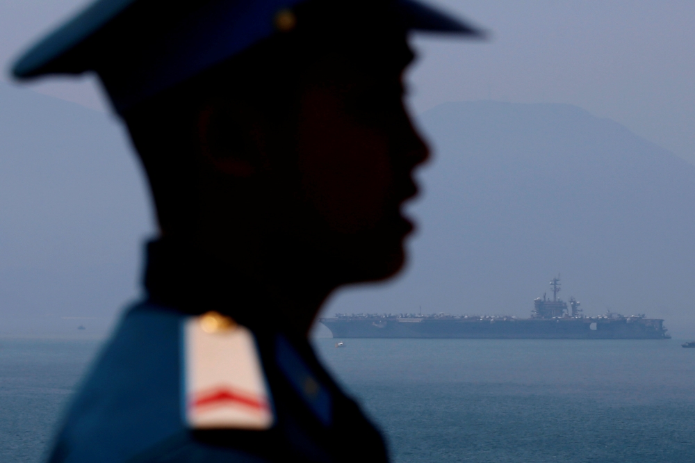 A Vietnamese soldier keeps watch in front of US aircraft carrier USS Carl Vinson after its arrival at a port in Danang, Vietnam March 5, 2018. Reuters/Kham
