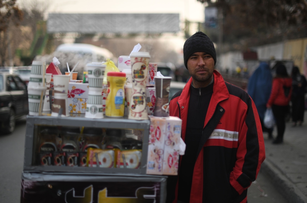File photo of Najibullah Sharyari waiting for customers at his coffee cart in Kabul, January 8, 2018.  / AFP / SHAH MARAI / 