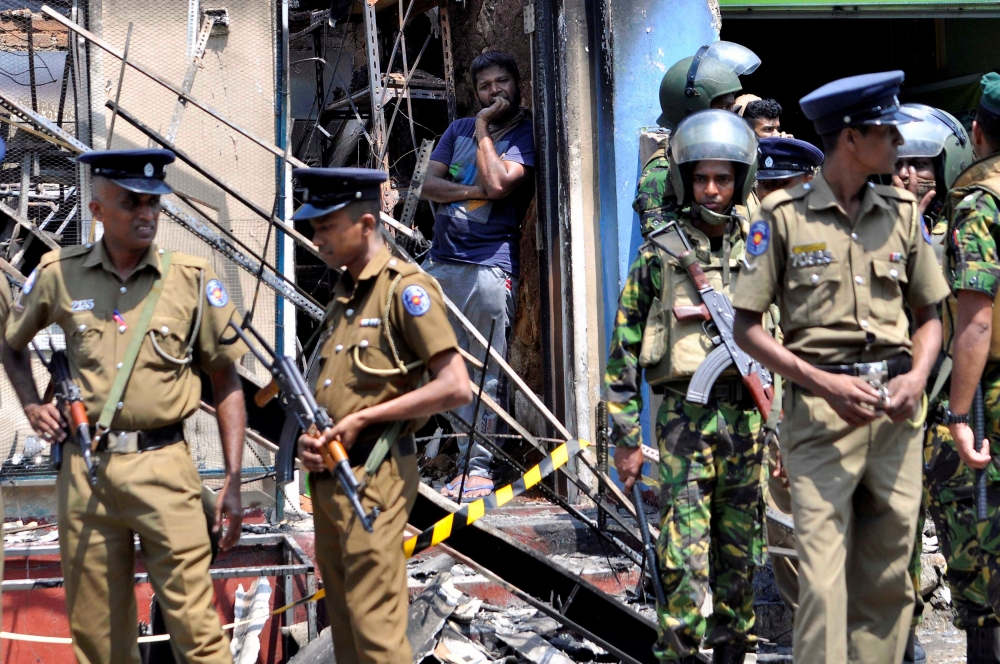 Sri Lanka's Special Task Force and Police officers stand guard near a burnt house after a clash between two communities in Digana, central district of Kandy, Sri Lanka March 6, 2018. REUTERS/Stringer 