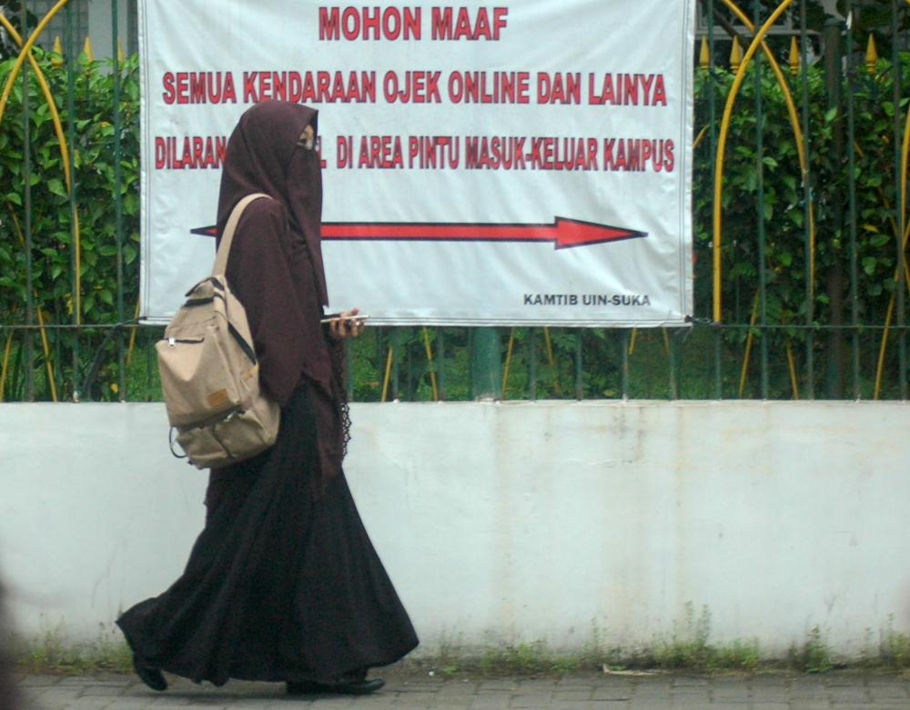 This photo taken on March 7, 2018 shows a student wearing a niqab face veil outside a university in Yogyakarta.  AFP / Agus WARDOYO
